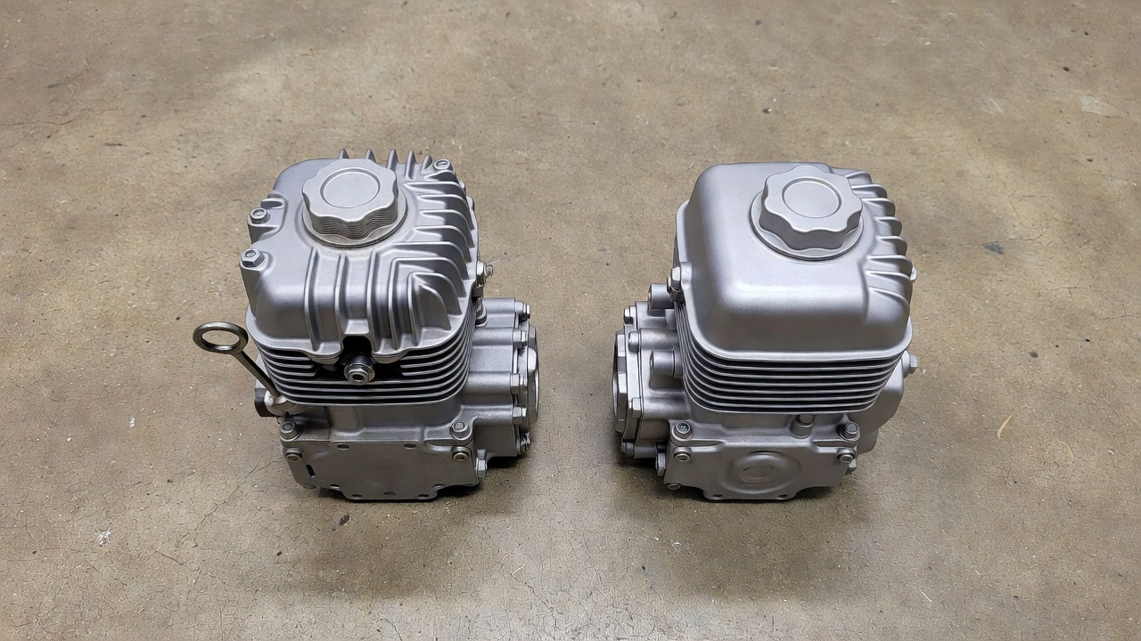 4-stroke lawn mower engine with oil dipstick alongside a 2-stroke engine with single fuel cap