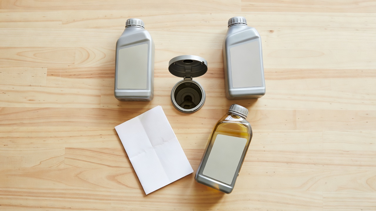 Types of motor oil bottles arranged next to a lawn mower engine.