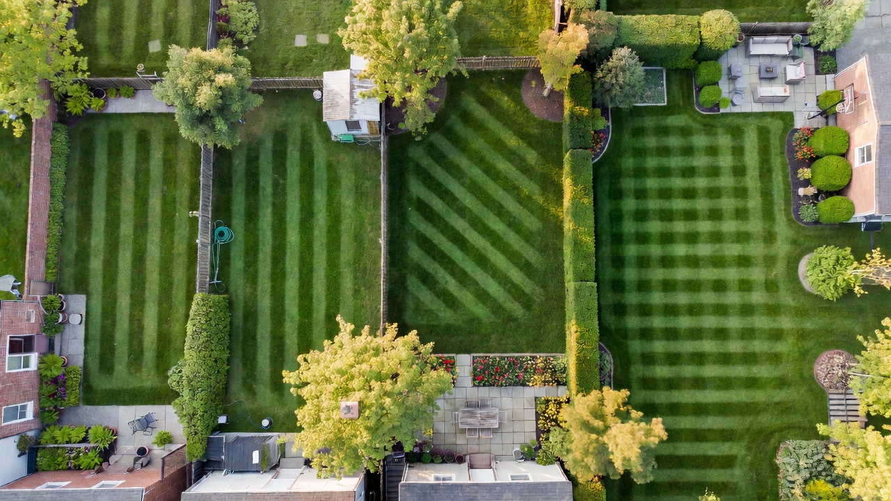 Aerial view of four residential yards of increasing size, all freshly mowed with stripe patterns