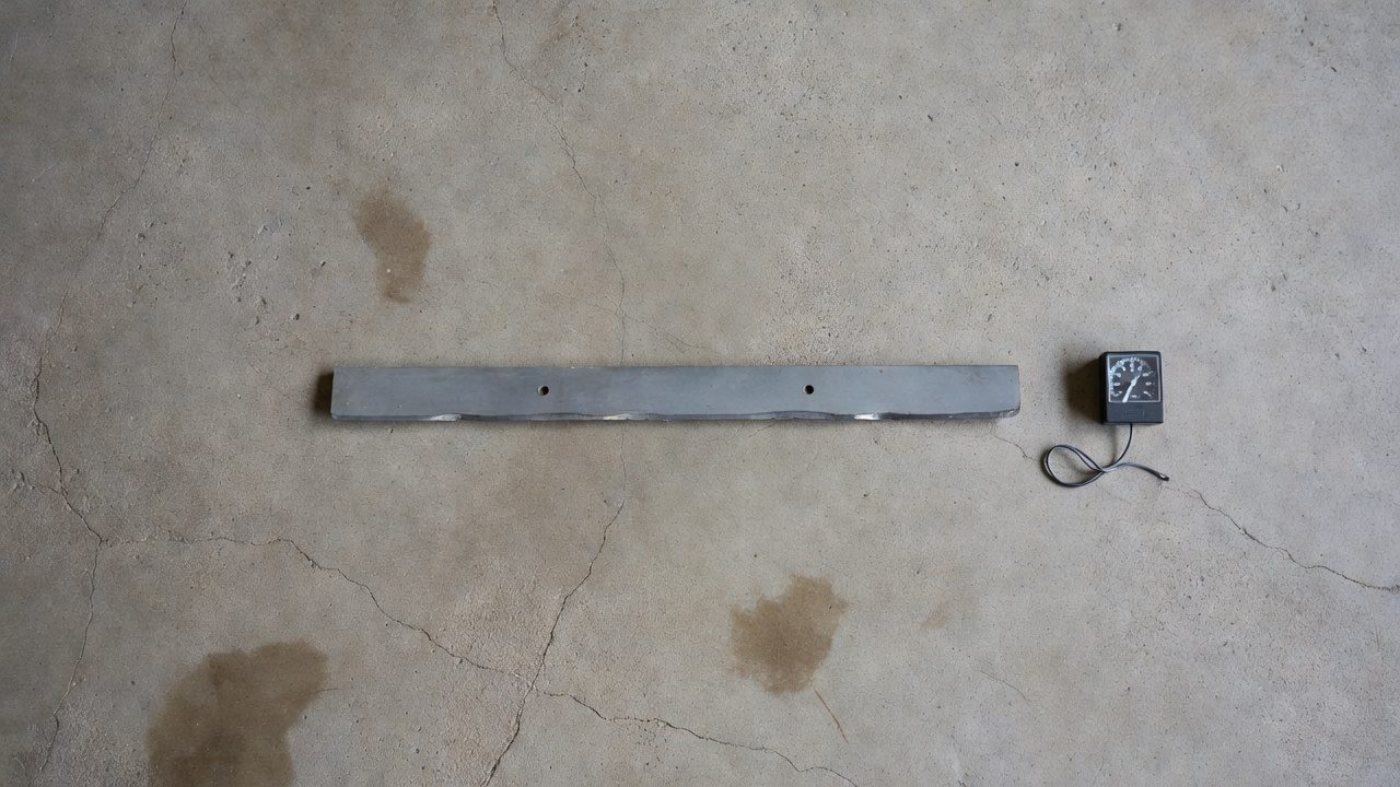 Mower blade next to a hourmeter on a garage floor illustrating runtime-based sharpening intervals