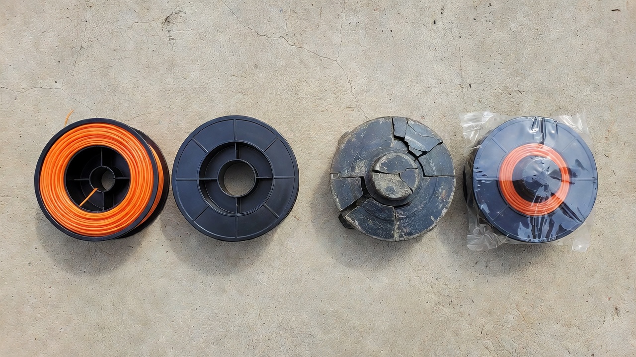 Old cracked trimmer head beside a new replacement head and a fresh spool, showing the difference between spool replacement and full head replacement