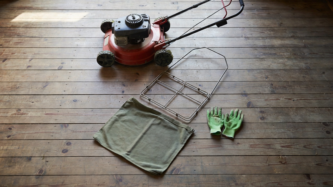 Grass catcher bag components, gloves, and lawn mower arranged before installation begins