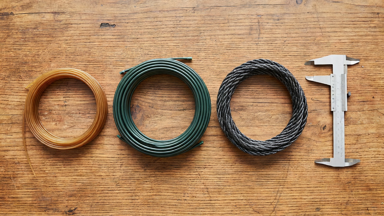 Various diameters and shapes of trimmer line arranged on a wooden surface.