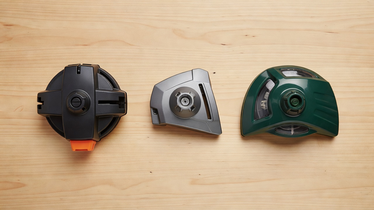 Three types of weed eater trimmer heads displayed on a workbench