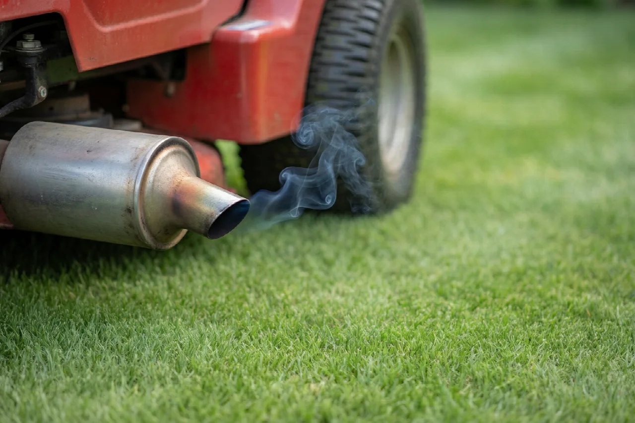 Riding lawn mower exhaust emitting a thin wisp of smoke.
